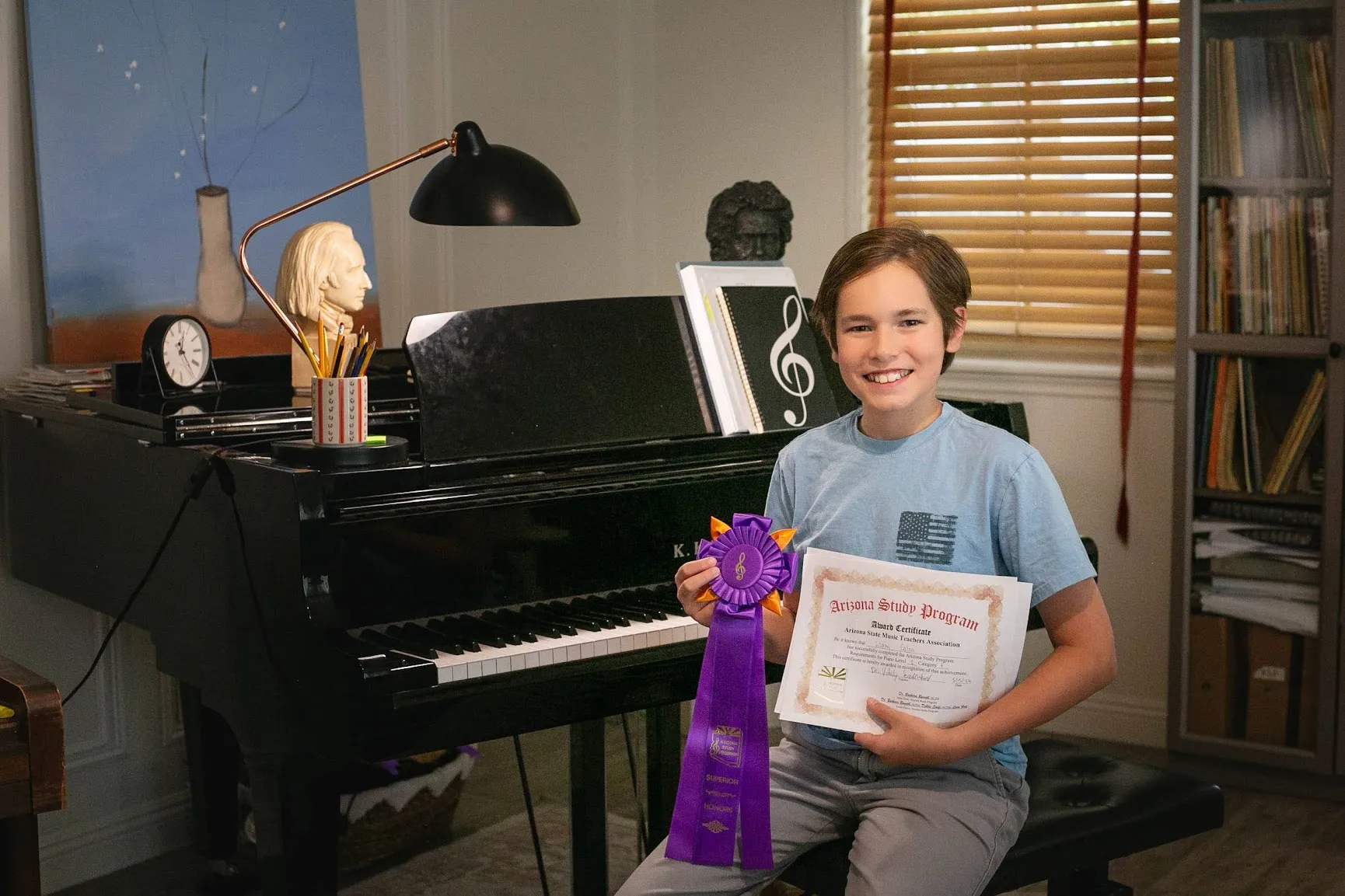 Piano student holding an Arizona Study Program certificate and award ribbon