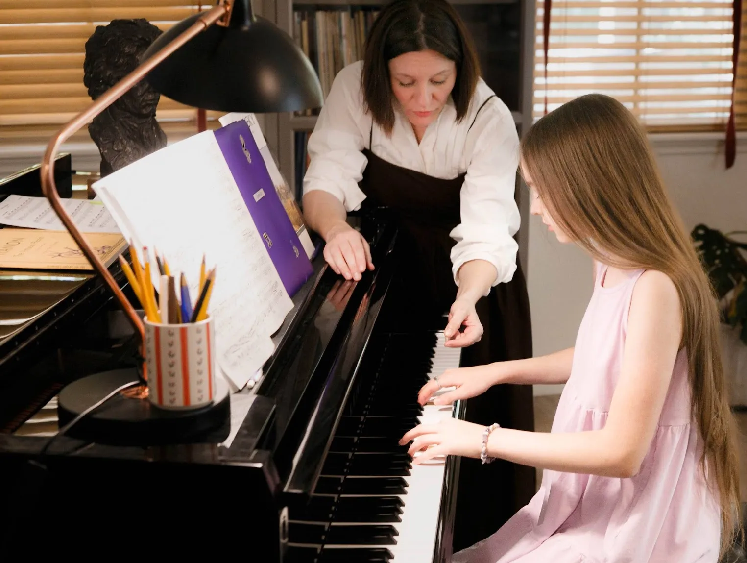 Piano teacher guiding a student during a lesson